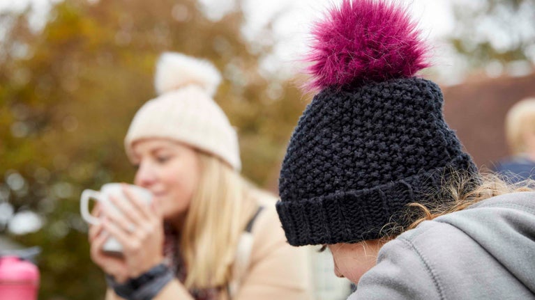 Visitors outside the cafe and shop in October at Stourhead, Wiltshire with hot drinks in October